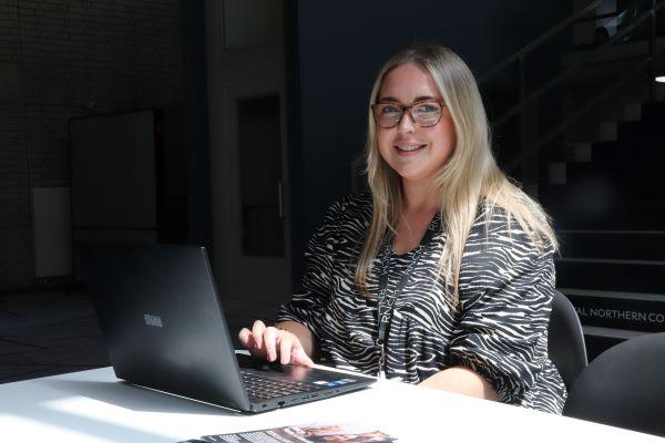 A procurement consultant working at a laptop smiling