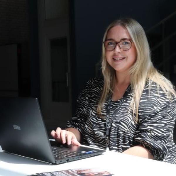 A procurement consultant working at a laptop smiling